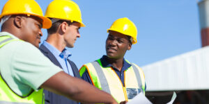 men in hardhats looking over plans and talking