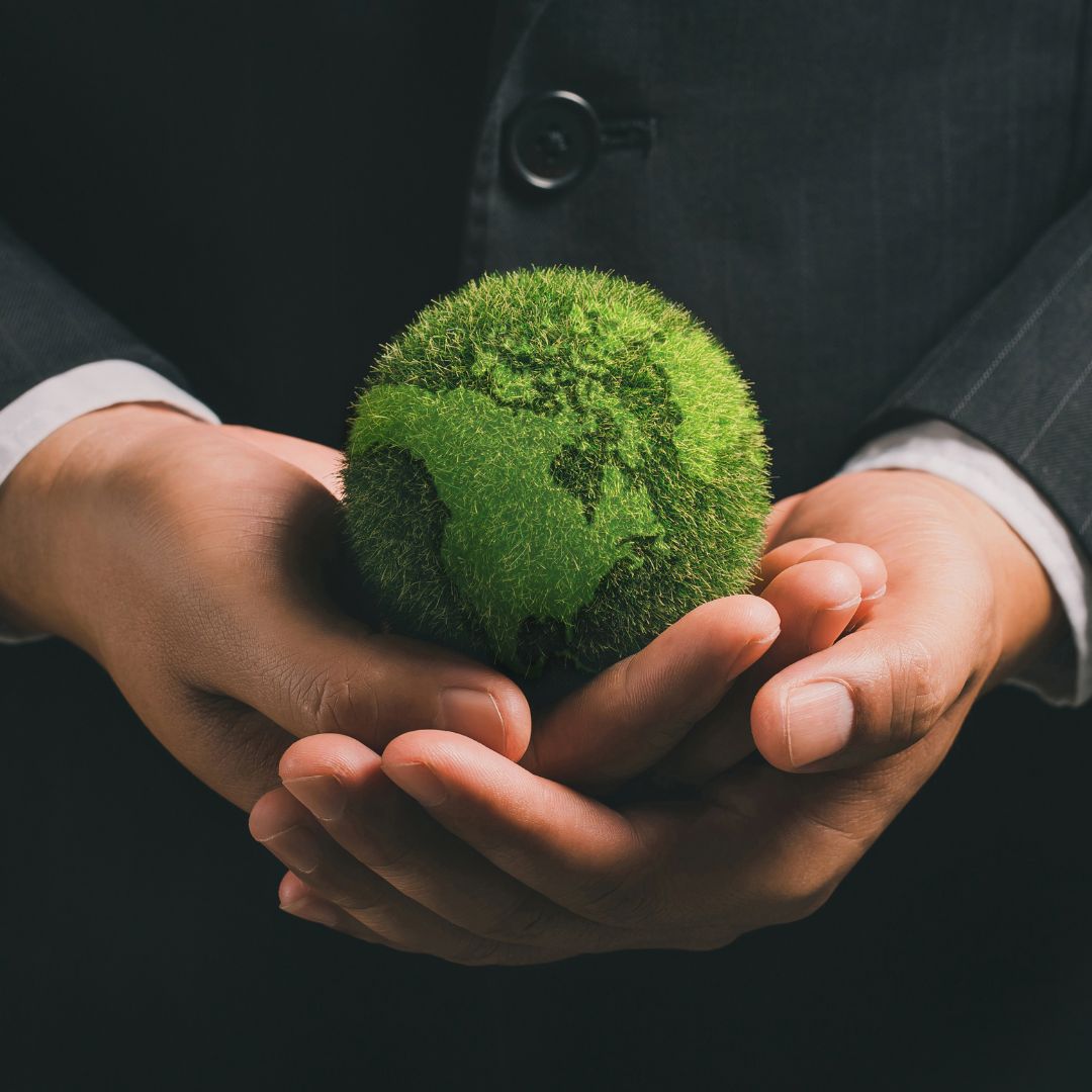 Person holding a green model Earth in their hands.